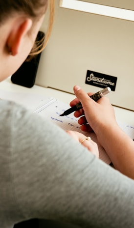 a woman sitting at a desk writing on a piece of paper