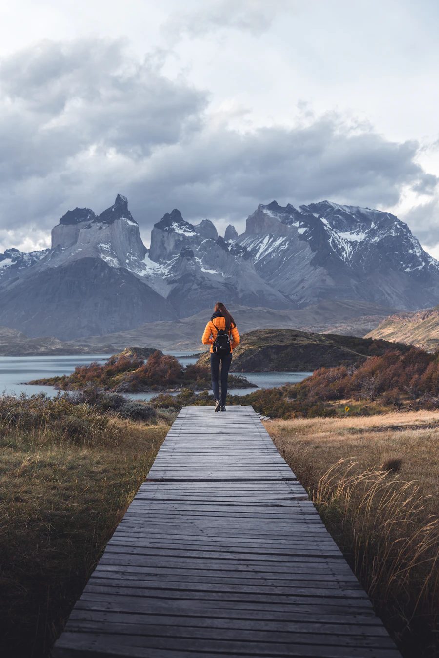 Hiker on a wooden walkway heading toward the mountains