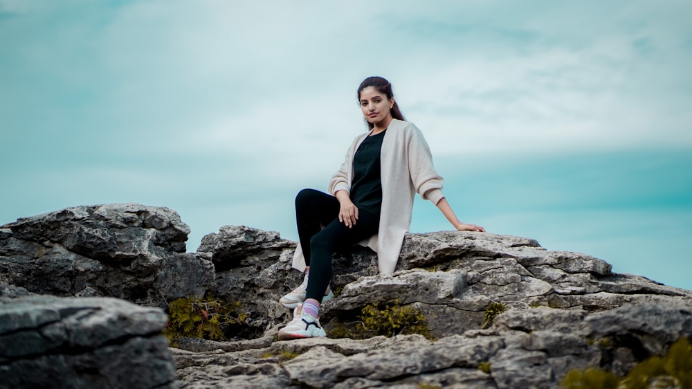 a woman sitting on top of a rock formation