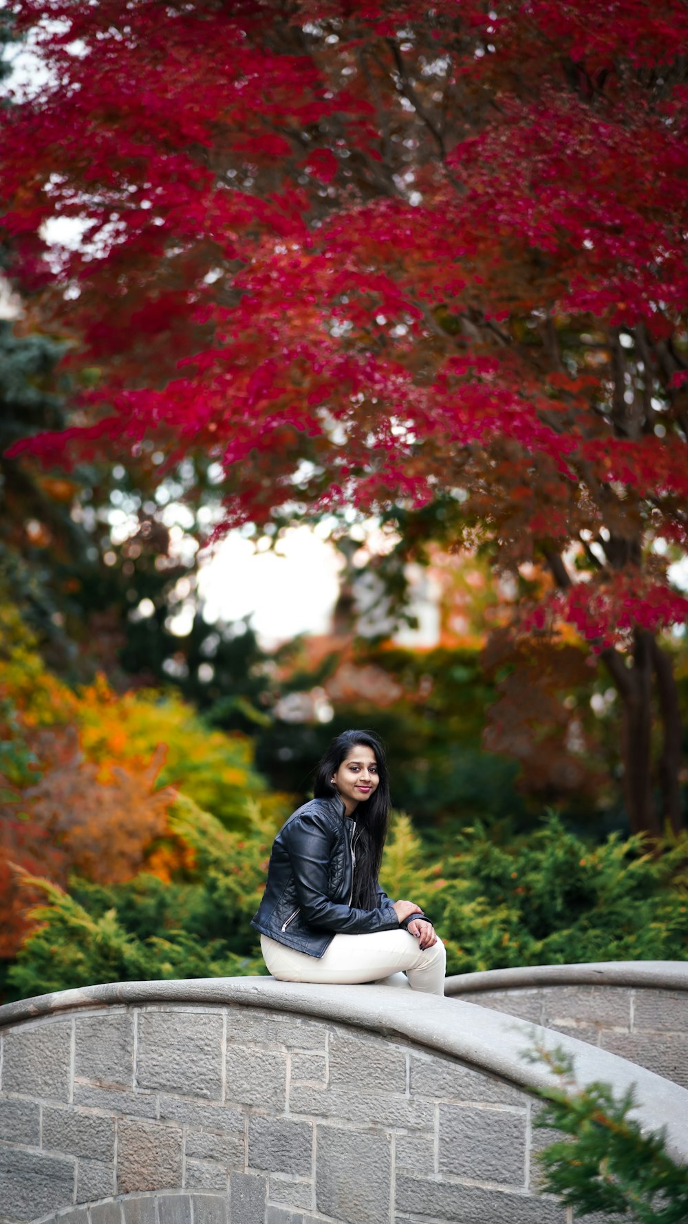 a woman sitting on a stone wall in a park