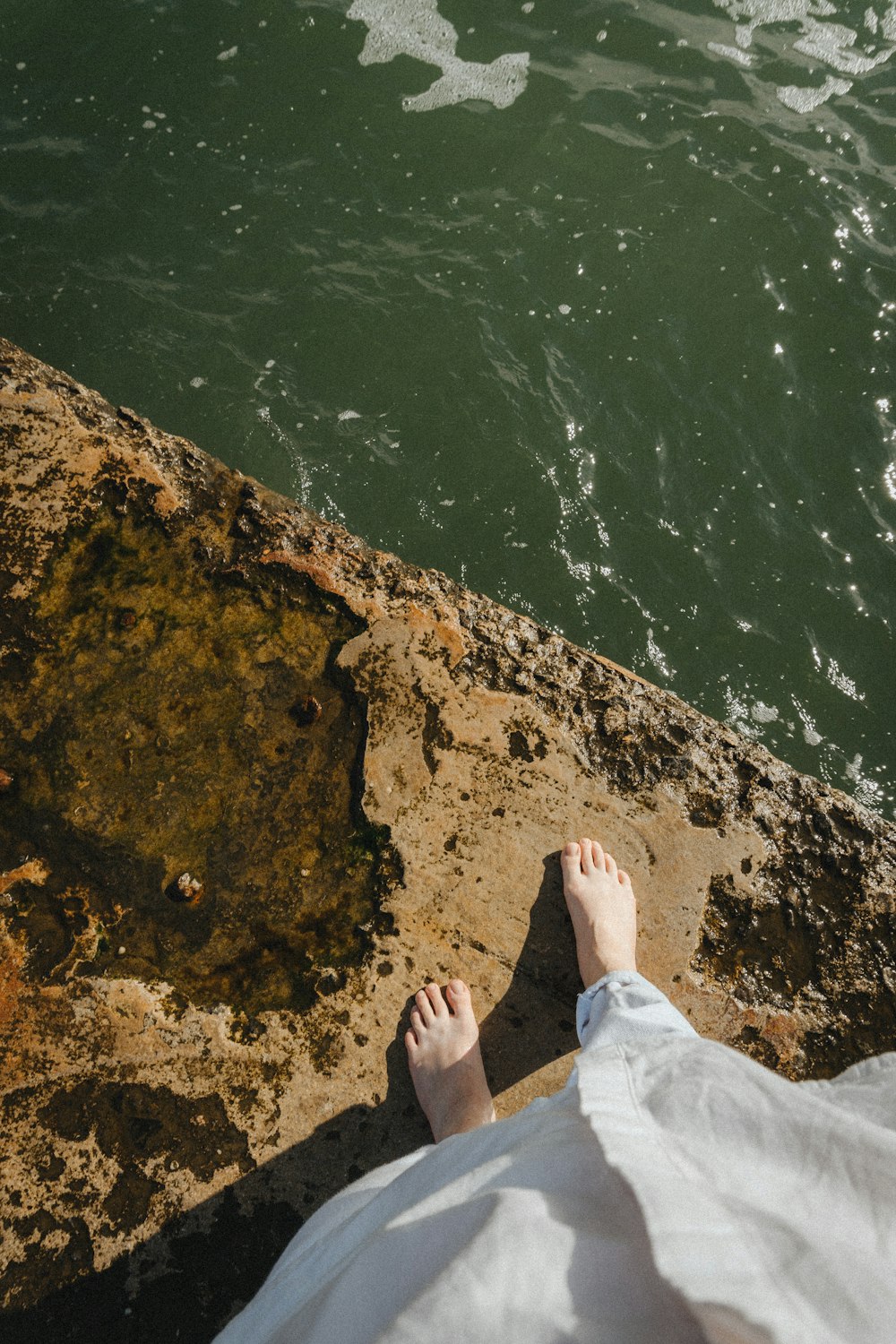 a person standing on a rock next to a body of water