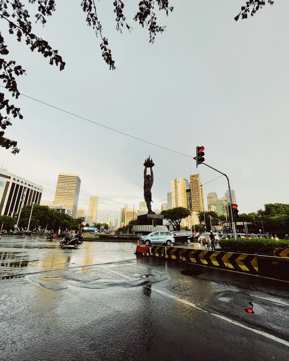 a wet street with a statue of a man on top of it