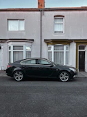 A sleek black sedan parked on a city street, ready for a school run.