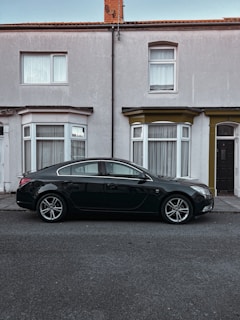 A sleek black sedan with a freshly repaired windshield parked outside a customer's home.