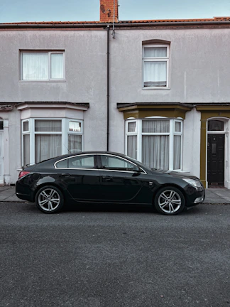 A sleek black sedan parked on a city street, ready for a school run.