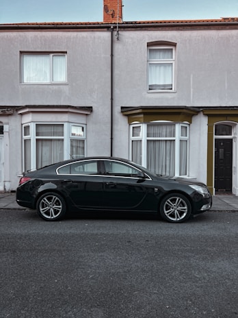 A sleek black sedan with a freshly repaired windshield parked outside a customer's home.