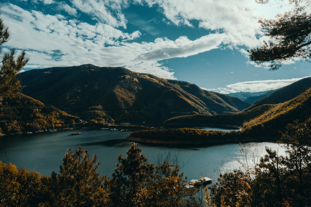 a lake surrounded by mountains under a cloudy sky