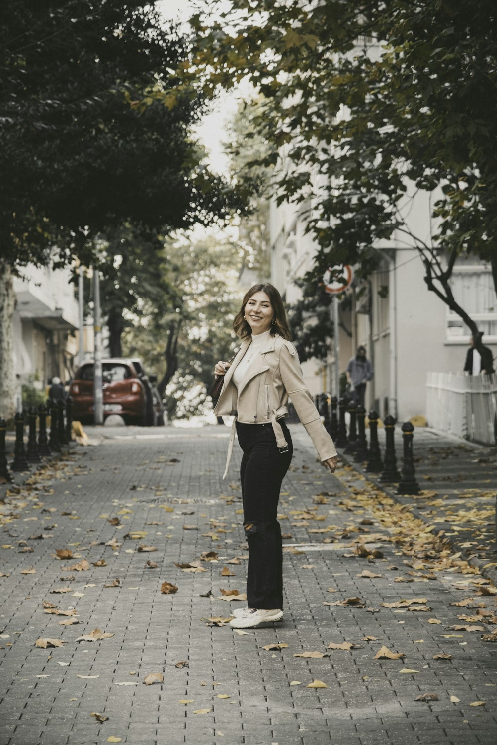 a woman walking down a street next to trees