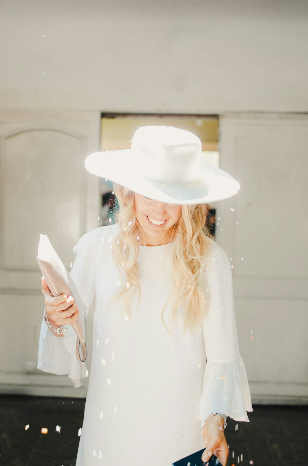 a woman wearing a white hat and holding a cell phone