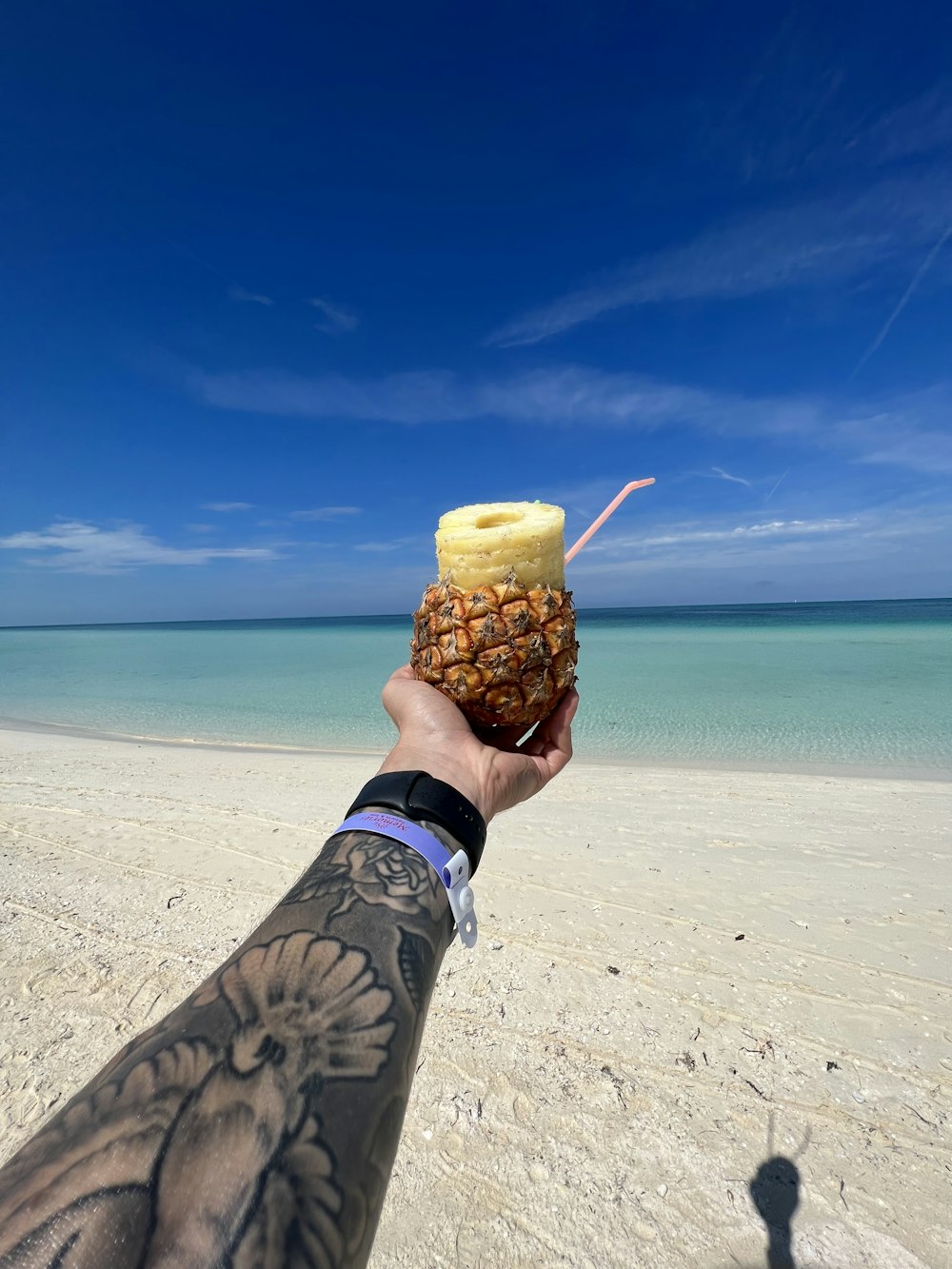 a person holding up a pineapple on a beach