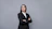 a woman in a business suit with her arms crossed