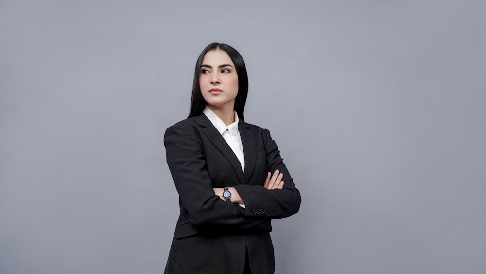 a woman in a business suit with her arms crossed
