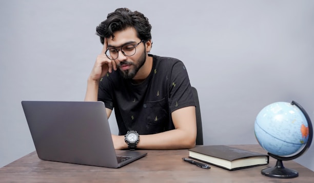 A student focused intently on a laptop screen, surrounded by study materials and notes.