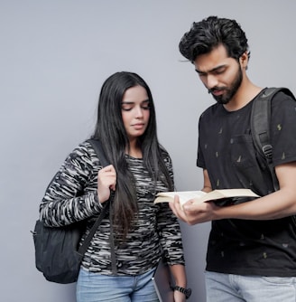 a man and a woman are looking at a book