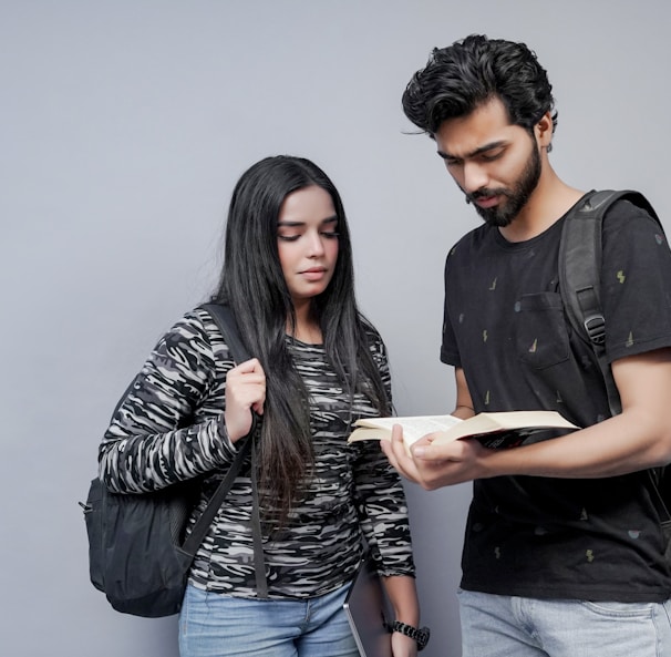 a man and a woman are looking at a book