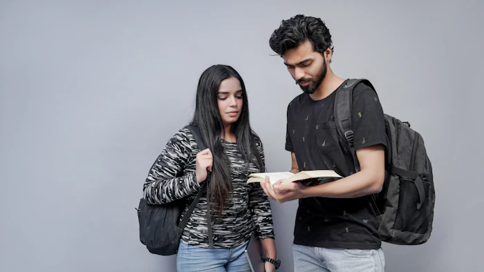 Two students with backpacks looking at notes together