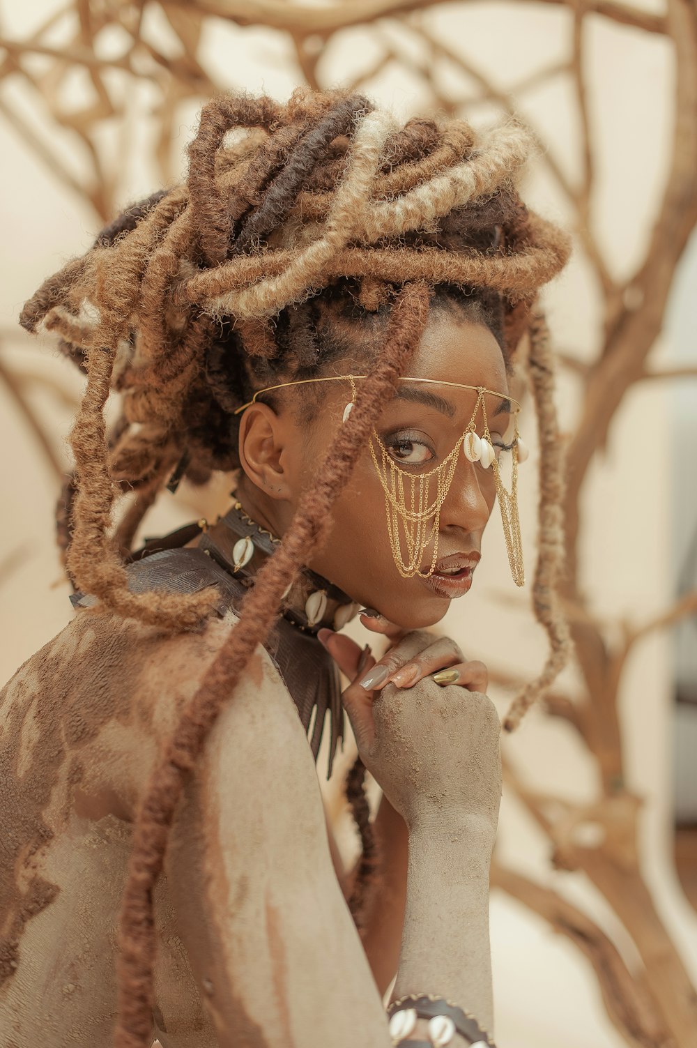 a woman with dreadlocks standing in front of a tree