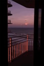Balcony view overlooking a beach at sunrise.