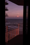 A spacious hotel balcony with a stunning view of the ocean at sunset.
