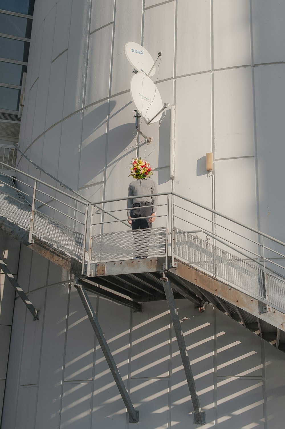 a man standing on a balcony next to a satellite dish