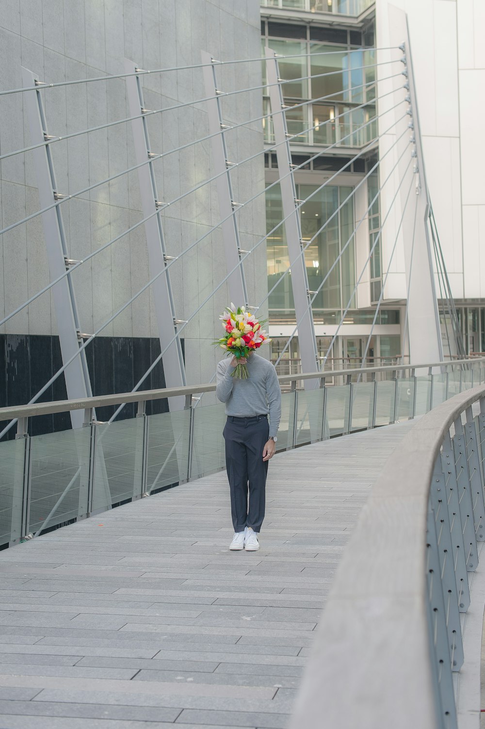 a woman walking across a bridge with a bunch of flowers on her head