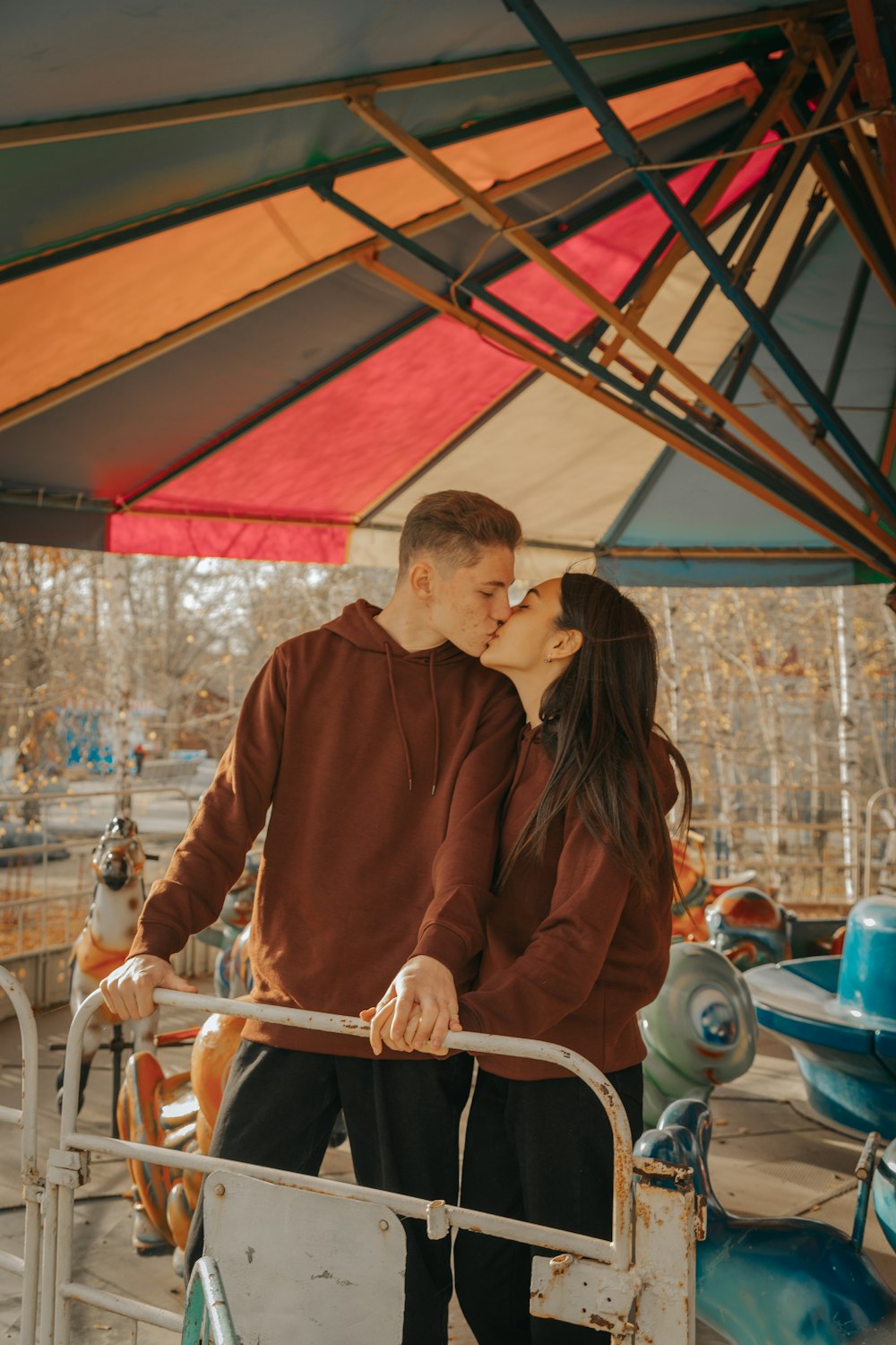 a man and a woman kissing in front of a carnival ride