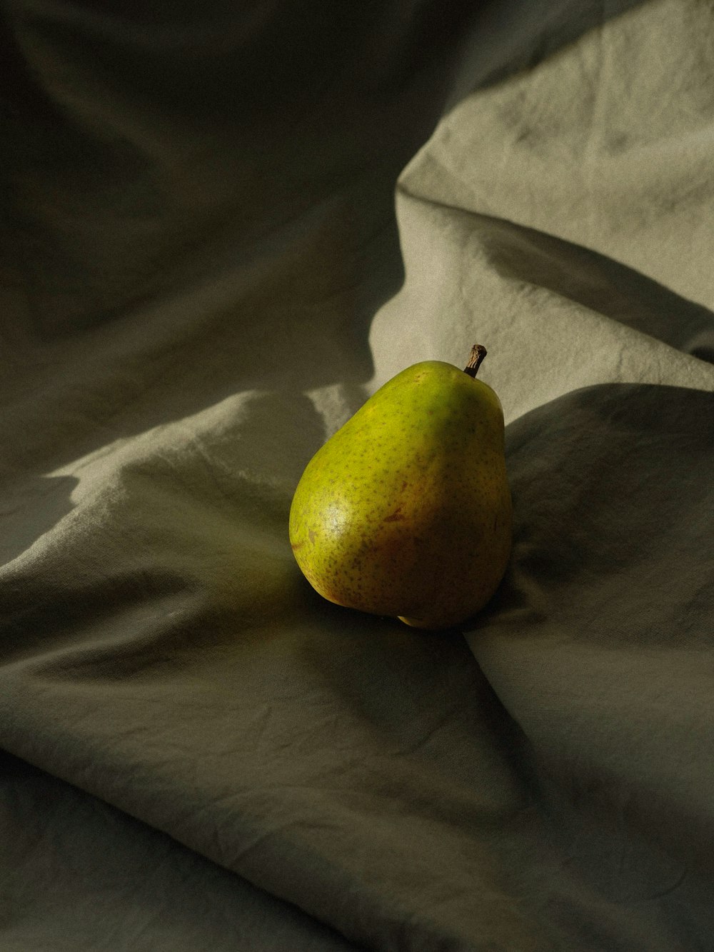 una pera sobre una sábana blanca