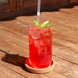 A red aloe fresh drink served in a stylish glass.