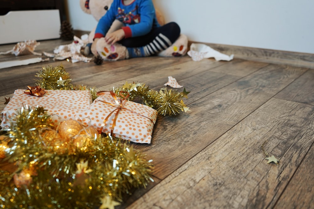 a little girl sitting on the floor with a wrapped present