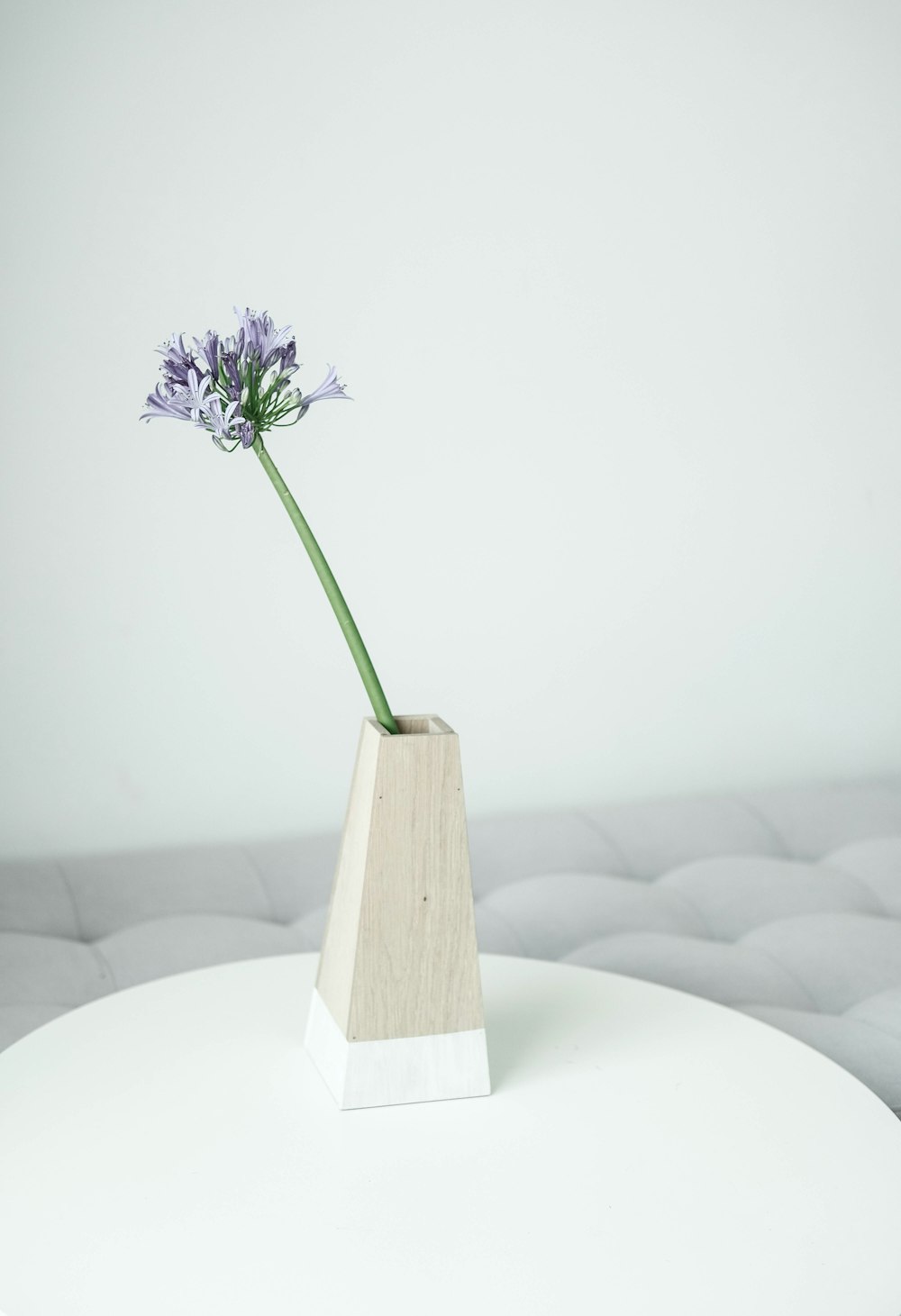 a white table with a flower in a wooden vase