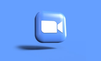 A 3D icon of a video camera, primarily blue with white camera details, appears to be floating against a solid blue background.