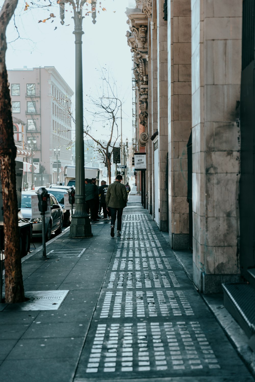 a man walking down a sidewalk next to a tall building