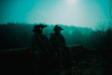 a couple of soldiers sitting next to each other with night vision binoculars