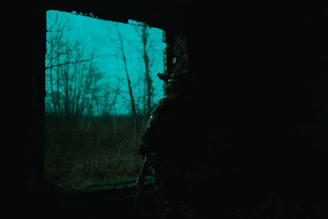 a man standing in the dark looking out a window