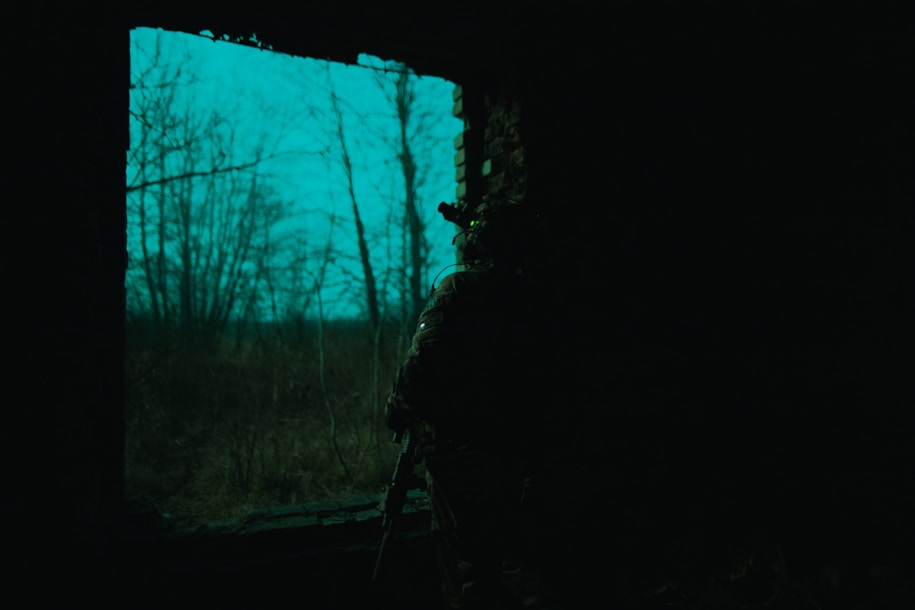 a man standing in the dark looking out a window