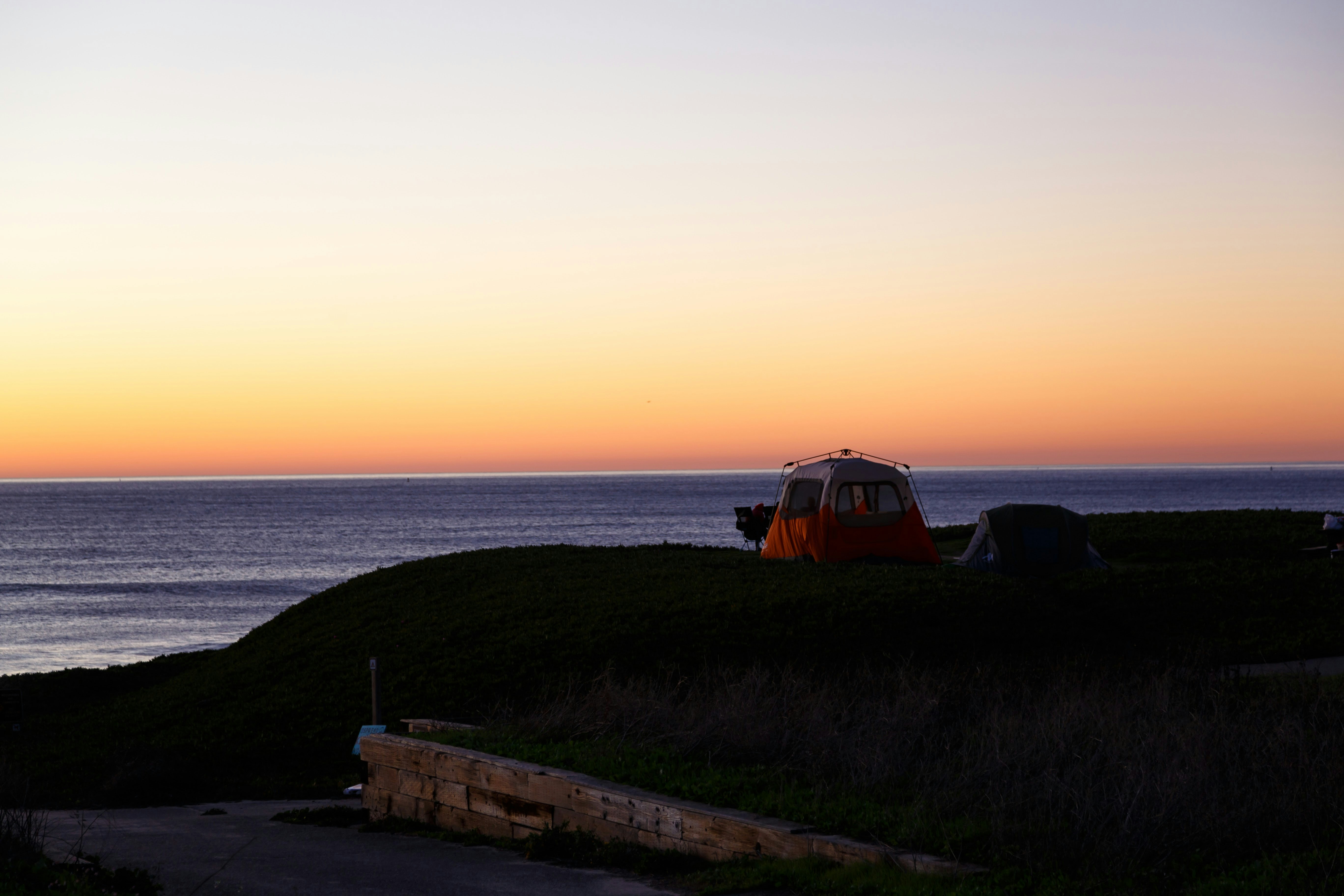 A couple of tents sitting on top of a lush green hillside photo – Free ...