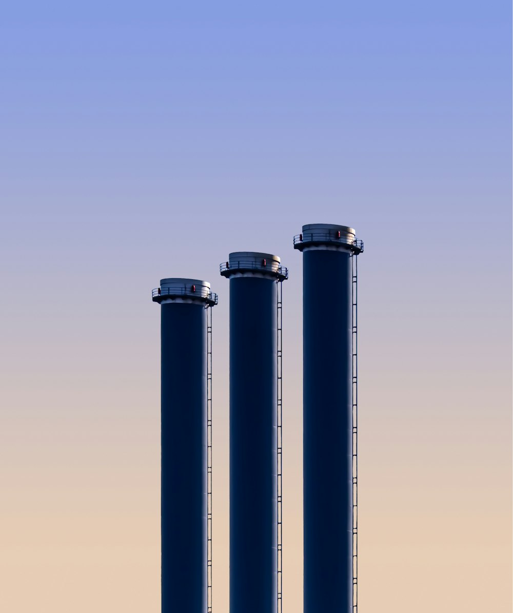 three blue cylinders are standing in the middle of a field