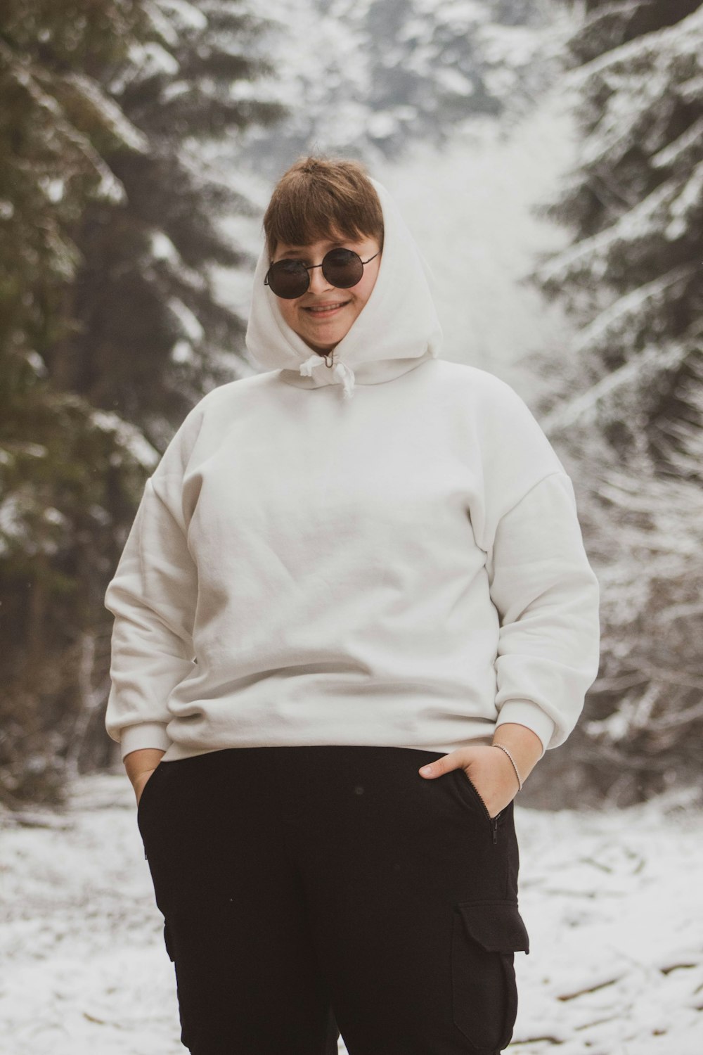 a woman standing in the snow wearing a white hoodie