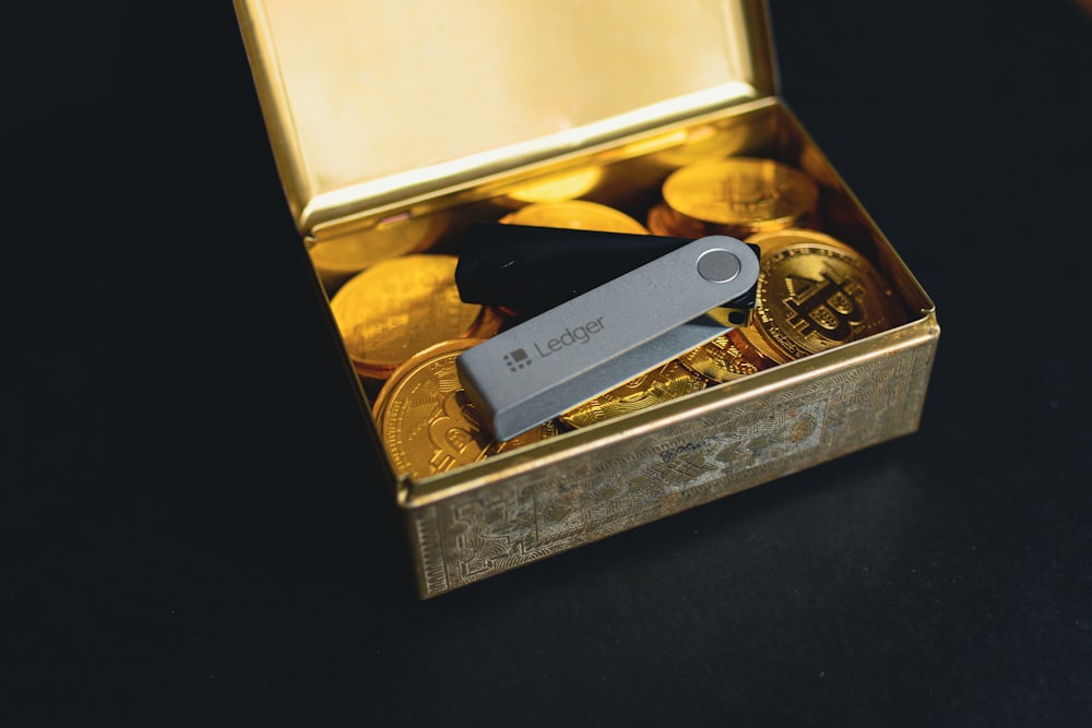a swiss army knife sitting in a box of gold coins