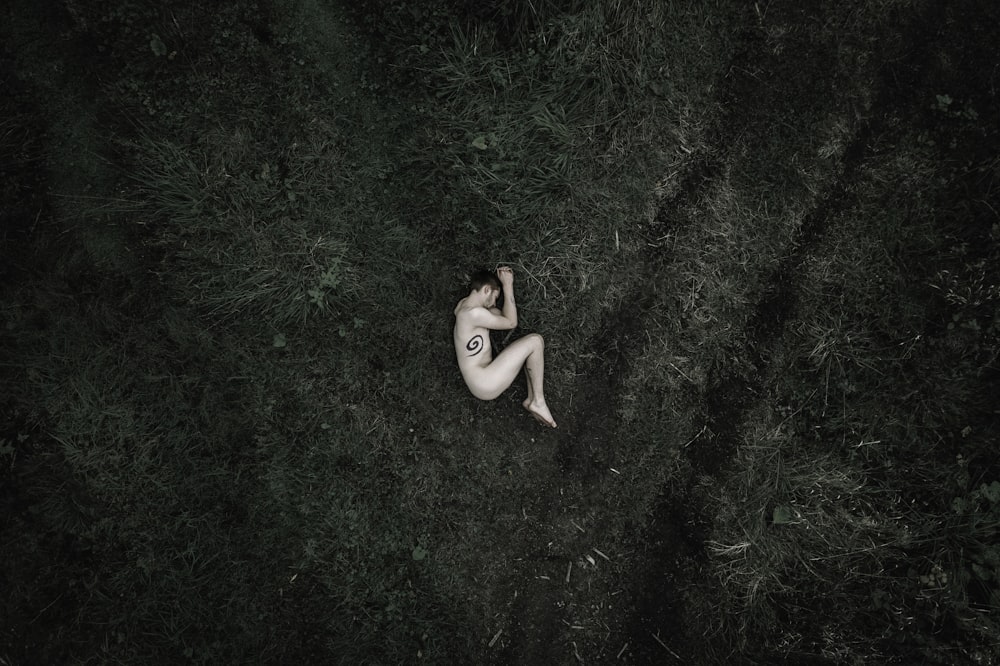 a naked woman laying on the ground in the grass