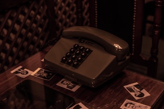 Close-up of a vintage telephone on a cozy wooden table with soft candlelight in the background.