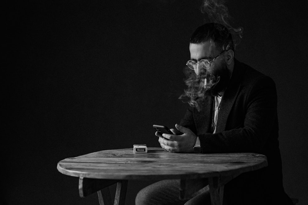 a man sitting at a table smoking a cigarette