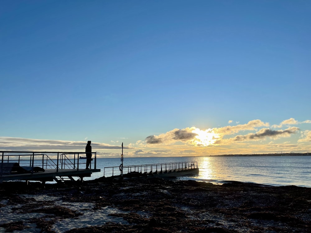 a person standing on a dock near the ocean