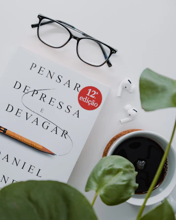 a book with a pen on top of it next to a cup of coffee