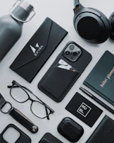 Collection of accessories including caps, mugs, and stickers arranged on a smooth black surface with soft shadows.