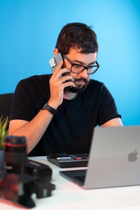 a man sitting at a desk talking on a cell phone