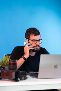 a man sitting at a desk talking on a cell phone