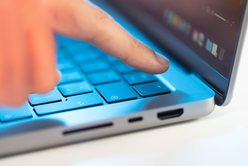 uma pessoa pressionando um botão em um laptop azul