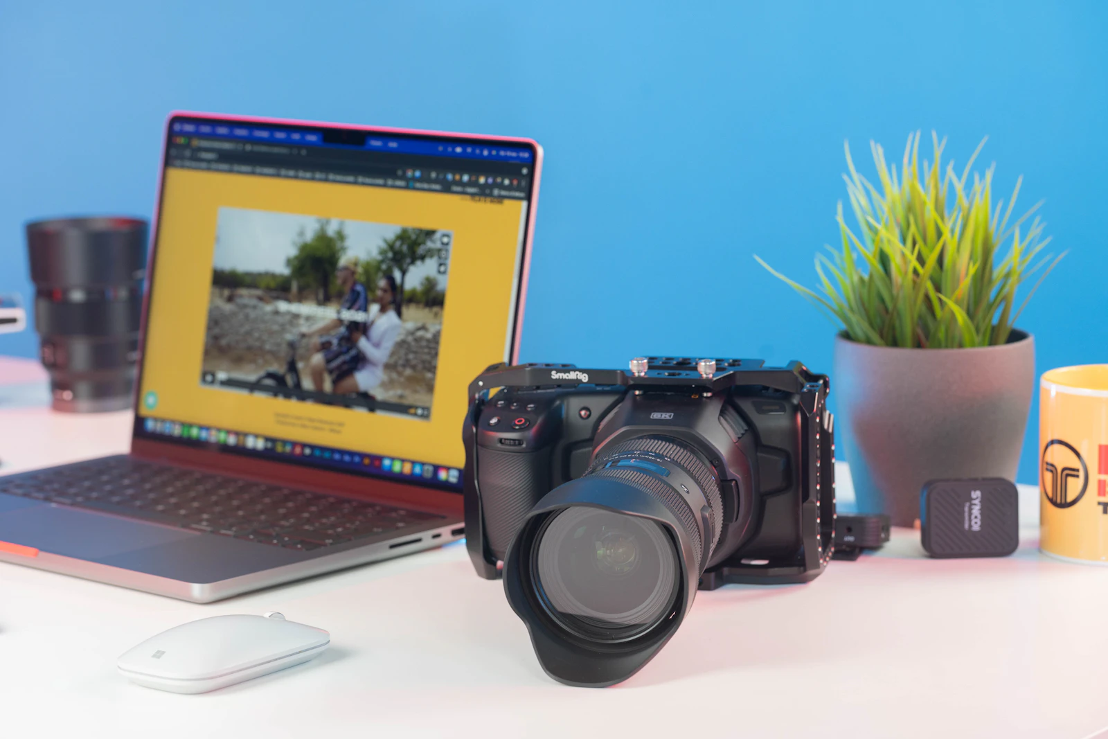 A laptop and camera beside each other on a desk.