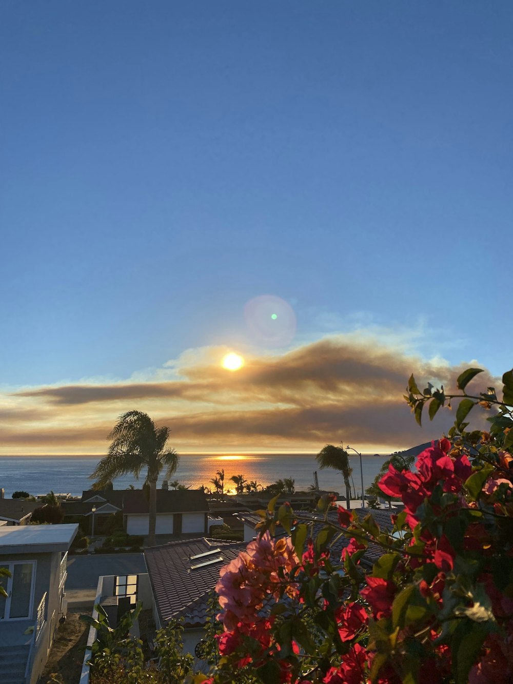 the sun is setting over the ocean and houses